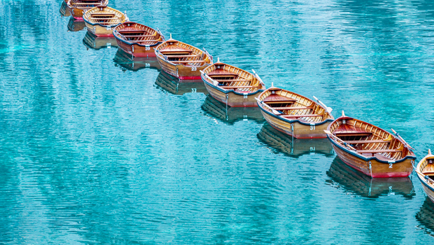Aerial view of traditional wooden rowboats lined up on the turquoise water of Lago di Braies in the Dolomites Italy.
