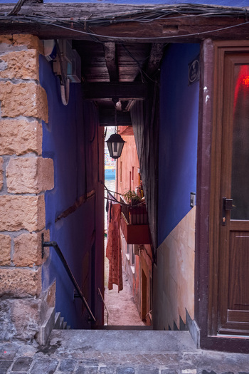 Pasai Donibane Spain 09 March 2026 View of a narrow passage with colorful blue and orange walls leading towards the harbor street in the historic village of Pasai Donibane.