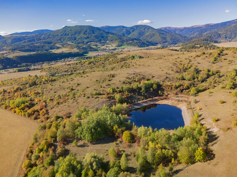Aerial view of the Gudronove jamy acid tar lagoons surrounded by autumn trees and rolling hills of the Low Tatras mountain range in Predajna Banskobystricky kraj Slovakia. Aerial view of the Gudronove jamy acid tar lagoons surrounded by autumn trees and rolling hills of the Low Tatras mountain range in Predajna Banskobystricky kraj Slovakia.