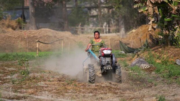 View of a woman operating a power tiller in a field Nepal. View of a woman operating a power tiller in a field Nepal.