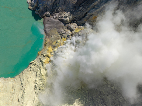 Aerial view of the turquoise acidic crater lake and thick sulfurous smoke rising from the mining site at Mount Ijen Ijen East Java Indonesia.