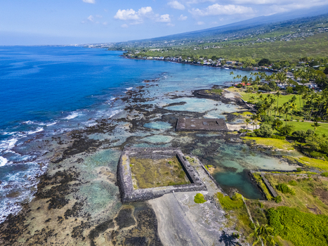 Aerial view of the ancient stone heiau at Kahalu u Beach Park along the volcanic coastline with turquoise waters and palm trees in Kailua Kona Hawaii United States. Aerial view of the ancient stone heiau at Kahalu u Beach Park along the volcanic coastline with turquoise waters and palm trees in Kailua Kona Hawaii United States.
