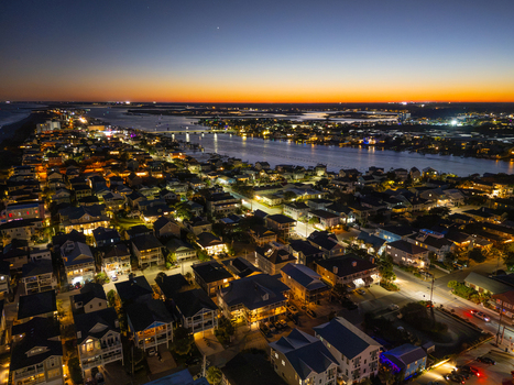 Aerial view of Wrightsville Beach at night featuring illuminated houses street lights and a bridge over the waterway in Wrightsville Beach North Carolina United States. Aerial view of Wrightsville Beach at night featuring illuminated houses street lights and a bridge over the waterway in Wrightsville Beach North Carolina United States.