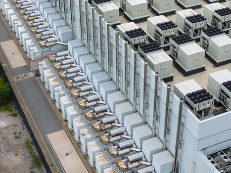 Aerial view of a data center rooftop featuring numerous industrial cooling units ventilation pipes and HVAC systems arranged in rows United Kingdom.
