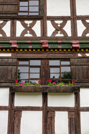 View of the traditional half timbered facade of Hennebergisches Museum Kloster Vessra with ornate wooden beams and colorful flower boxes in Kloster Vessra Thuringen Germany.