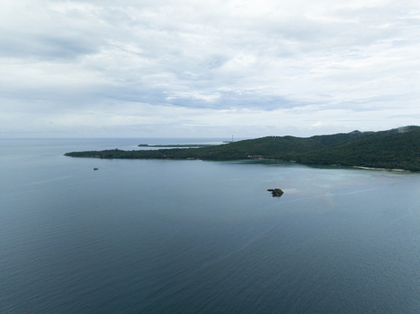 Aerial view of deep blue waters embrace the lush green island under a soft cloudy sky Karimunjawa Central Java Indonesia.