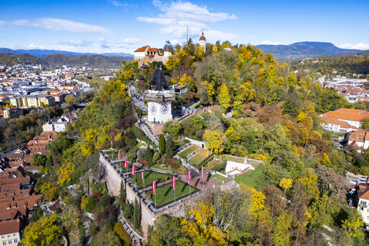 Aerial view of the clock tower the Grazer Schlossberg nestled amidst vibrant autumn foliage stands proud against the skyline Graz Styria Austria.