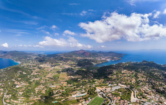Aerial view of the coastal landscape surrounding Porto Azzurro featuring rolling hills agricultural fields and the blue Mediterranean sea in Porto Azzurro Toscana Italy.