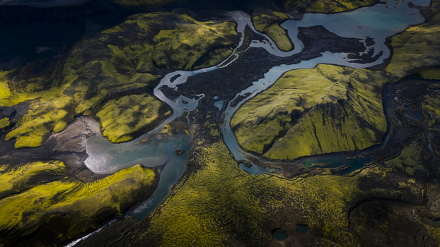 Aerial view of Langisjor lake surrounded by vibrant green moss covered volcanic hills and winding glacial waterways in Vik Skaftarhreppur Iceland. Aerial view of Langisjor lake surrounded by vibrant green moss covered volcanic hills and winding glacial waterways in Vik Skaftarhreppur Iceland.