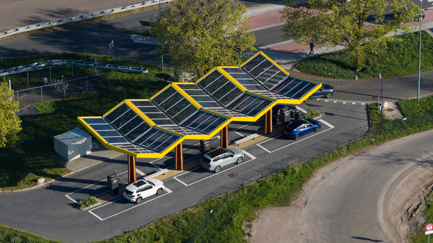 Bant Netherlands 23 April 2026 Aerial view of Fastned Charging Station featuring a yellow solar panel roof with electric cars parked in charging bays surrounded by green trees. Bant Netherlands 23 April 2026 Aerial view of Fastned Charging Station featuring a yellow solar panel roof with electric cars parked in charging bays surrounded by green trees.