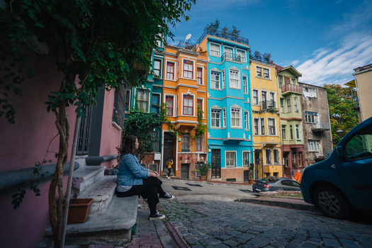 Istanbul Turkiye 06 October 2019 View of a woman sitting on steps amidst the vibrant colorful facades of buildings in Balat a historic district. Istanbul Turkiye 06 October 2019 View of a woman sitting on steps amidst the vibrant colorful facades of buildings in Balat a historic district.