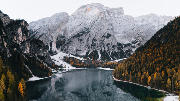 Aerial view of Lake Braies surrounded by snow dusted mountain peaks and dense forests with autumn colors in Braies Trentino Alto Adige Italy. Aerial view of Lake Braies surrounded by snow dusted mountain peaks and dense forests with autumn colors in Braies Trentino Alto Adige Italy.