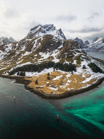 Aerial view of where turquoise waters meet the rugged snow dusted landscape under a cloudy sky Kåkernbrua Nordland Norway. Aerial view of where turquoise waters meet the rugged snow dusted landscape under a cloudy sky Kåkernbrua Nordland Norway.