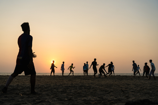 Sri Lanka 23 January 2026 View of young men playing football on a sandy beach during a golden sunset over the Indian Ocean.