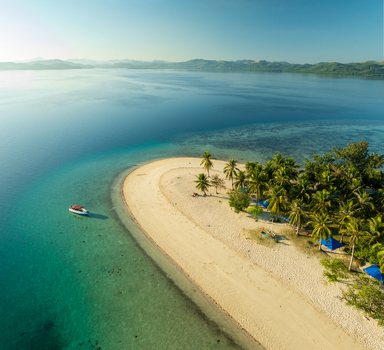 Aerial view of Pass Island with its pristine white sand beach lush palm trees and a small boat anchored in the clear turquoise waters of the coral reef in Coron Philippines. Aerial view of Pass Island with its pristine white sand beach lush palm trees and a small boat anchored in the clear turquoise waters of the coral reef in Coron Philippines.