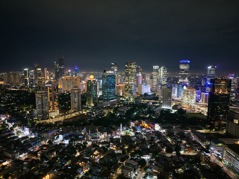 Aerial view of the illuminated Semanggi interchange and the dense Jakarta skyline at night with glowing skyscrapers and urban lights in Setiabudi Jakarta Indonesia. Aerial view of the illuminated Semanggi interchange and the dense Jakarta skyline at night with glowing skyscrapers and urban lights in Setiabudi Jakarta Indonesia.