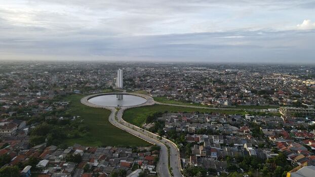 Aerial view of the circular reservoir and surrounding urban landscape with a tall building in the distance in Bekasi Barat West Java Indonesia. Aerial view of the circular reservoir and surrounding urban landscape with a tall building in the distance in Bekasi Barat West Java Indonesia.