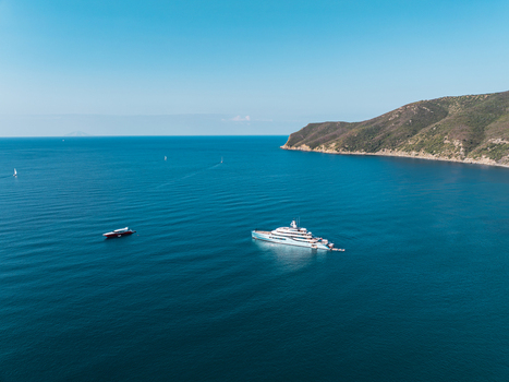 Aerial view of the luxury yacht Netto II anchored in the calm blue waters of Lacona Bay off the coast of Elba island surrounded by coastal hills in Lacona Tuscany Italy.