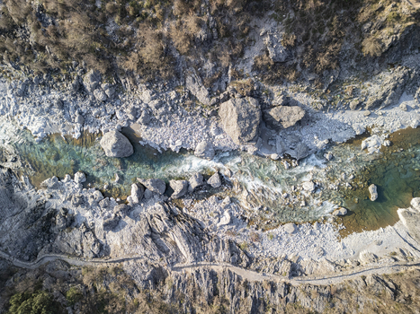 Aerial view of the turquoise waters of the Kiri River flowing through a rugged rocky riverbed with large boulders and a winding path along the bank in Shkoder Qarku i Shkodres Albania. Aerial view of the turquoise waters of the Kiri River flowing through a rugged rocky riverbed with large boulders and a winding path along the bank in Shkoder Qarku i Shkodres Albania.