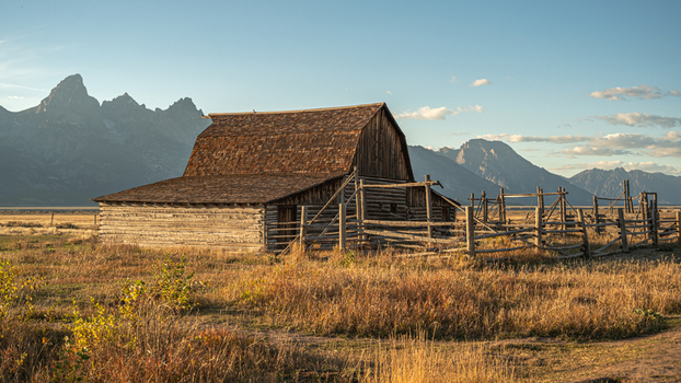 View of the historic Moulton Barn in Jackson Hole with the Teton mountain range in the background under golden hour light in Teton County Wyoming United States.