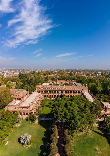Aerial view of Islamia College University Peshawar featuring historic brick architecture lush gardens and trees under a clear blue sky in Peshawar Khyber Pakhtunkhwa Pakistan. Aerial view of Islamia College University Peshawar featuring historic brick architecture lush gardens and trees under a clear blue sky in Peshawar Khyber Pakhtunkhwa Pakistan.
