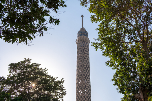 View of the Cairo Tower pierces the sky framed by the lush green foliage of surrounding trees under a bright sun Zamalek Cairo Governorate Egypt. View of the Cairo Tower pierces the sky framed by the lush green foliage of surrounding trees under a bright sun Zamalek Cairo Governorate Egypt.