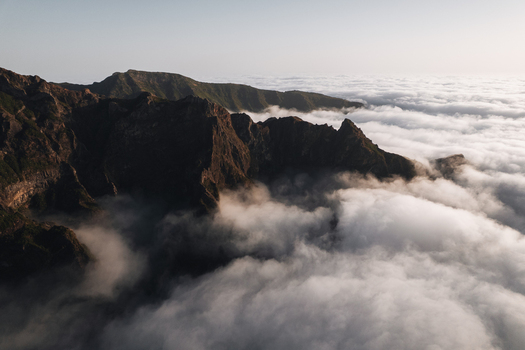 Aerial view of rugged mountain peaks piercing through a serene sea of clouds creating a dramatic contrast of earth and sky Pico do Areeiro Madeira Portugal.