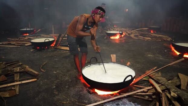 View of a man stirring milk over an open fire in Bangladesh. View of a man stirring milk over an open fire in Bangladesh.