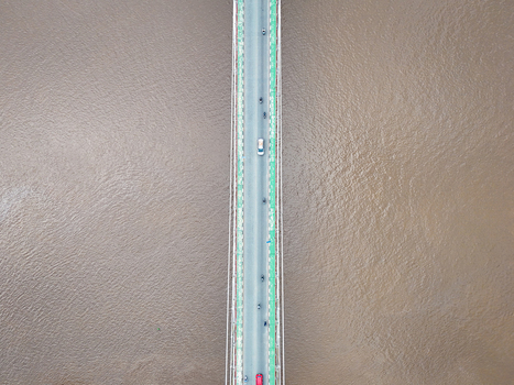 Aerial view of Barito Bridge spanning over the wide Barito River with vehicles driving across the asphalt surface in Kecamatan Alalak Kalimantan Selatan Indonesia.