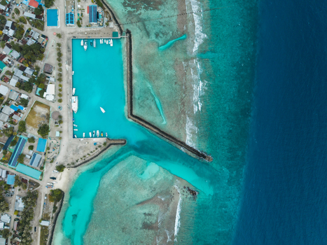 Aerial view of turquoise waters embrace the harbor contrasting with the buildings on the coast Vashafaru Island Thiladhummathi Atoll Maldives. Aerial view of turquoise waters embrace the harbor contrasting with the buildings on the coast Vashafaru Island Thiladhummathi Atoll Maldives.