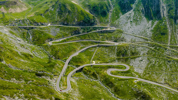 Aerial view of the winding Transfagarasan mountain road with sharp curves and steep green slopes in the Carpathian Mountains Curtea de Arges Judetul Arges Romania.