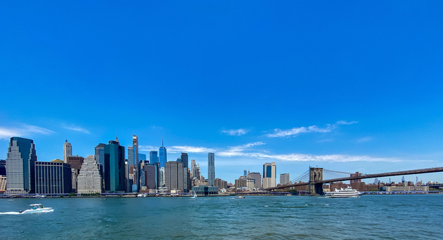 View of the Manhattan skyline and the Brooklyn Bridge over the East River under a clear blue sky in New York New York United States. View of the Manhattan skyline and the Brooklyn Bridge over the East River under a clear blue sky in New York New York United States.