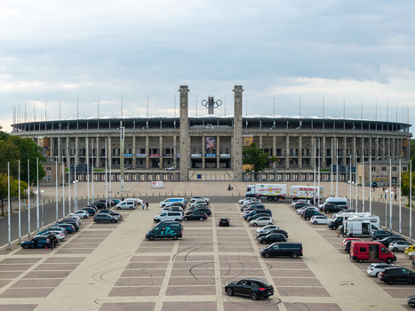 Berlin Germany 26 September 2026 Aerial view of Olympiastadion Berlin with its historic stone facade iconic Olympic rings and a large parking area filled with vehicles.
