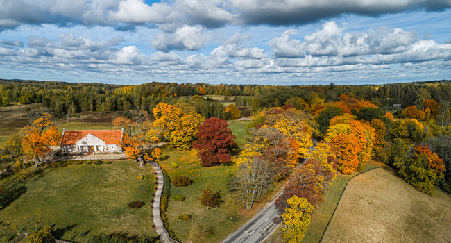 Aerial view of the historic Sigulda Castle manor surrounded by vibrant autumn foliage a winding wooden path and lush green lawns in Sigulda Sigulda Municipality Latvia. Aerial view of the historic Sigulda Castle manor surrounded by vibrant autumn foliage a winding wooden path and lush green lawns in Sigulda Sigulda Municipality Latvia.