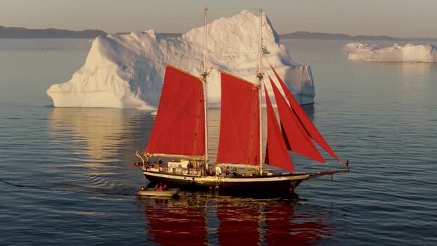 Aerial view of a schooner with red sails near an iceberg Greenland. Aerial view of a schooner with red sails near an iceberg Greenland.