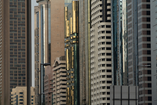 View of modern skyscrapers with glass facades and golden architectural details in the financial district of Dubai Dubai United Arab Emirates. View of modern skyscrapers with glass facades and golden architectural details in the financial district of Dubai Dubai United Arab Emirates.