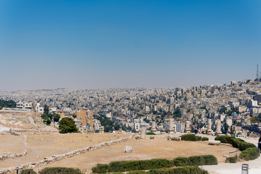 View of the ancient ruins of the Amman Citadel overlooking the sprawling urban cityscape of Amman under a clear blue sky in Amman Amman Governorate Jordan.