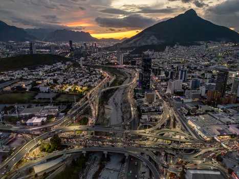 Aerial view of the illuminated highway interchange and city skyline nestled against the backdrop of the Sierra Madre mountains at dusk Monterrey Nuevo Leon Mexico. Aerial view of the illuminated highway interchange and city skyline nestled against the backdrop of the Sierra Madre mountains at dusk Monterrey Nuevo Leon Mexico.