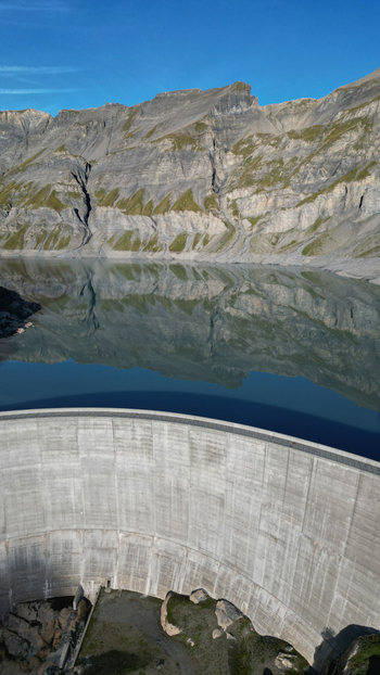 Aerial view of the Vieux Emosson dam and lake reflecting the surrounding rocky alpine mountains under a clear blue sky in Finhaut Valais Switzerland. Aerial view of the Vieux Emosson dam and lake reflecting the surrounding rocky alpine mountains under a clear blue sky in Finhaut Valais Switzerland.