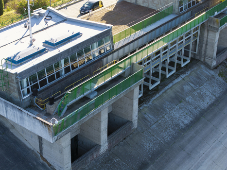 Aerial view of Niedzica Hydroelectric Power Plant featuring concrete structures green railings and a building with large windows in Niedzica Lesser Poland Poland. Aerial view of Niedzica Hydroelectric Power Plant featuring concrete structures green railings and a building with large windows in Niedzica Lesser Poland Poland.