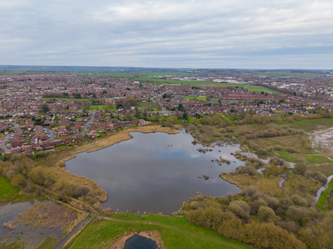 Aerial view of Doxey Marshes featuring wetlands and a central lake surrounded by residential areas and green fields in Stafford England United Kingdom. Aerial view of Doxey Marshes featuring wetlands and a central lake surrounded by residential areas and green fields in Stafford England United Kingdom.