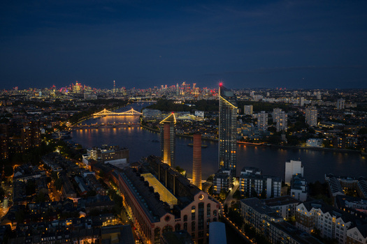 Aerial view of Lots Road Power Station and the River Thames at night with illuminated chimneys and the city skyline under a twilight sky London England United Kingdom. Aerial view of Lots Road Power Station and the River Thames at night with illuminated chimneys and the city skyline under a twilight sky London England United Kingdom.