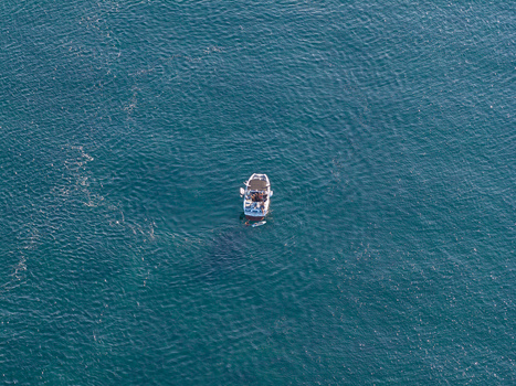 Aerial view of a small motorboat floating on the deep blue Mediterranean Sea near the coast of Antibes Provence Alpes Cote d Azur France. Aerial view of a small motorboat floating on the deep blue Mediterranean Sea near the coast of Antibes Provence Alpes Cote d Azur France.