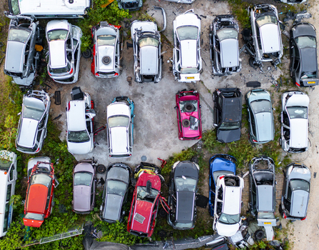 Aerial view of a car junk yard with various wrecked vehicles parked in rows on a concrete lot surrounded by greenery in Petah Tikva Center District Israel. Aerial view of a car junk yard with various wrecked vehicles parked in rows on a concrete lot surrounded by greenery in Petah Tikva Center District Israel.