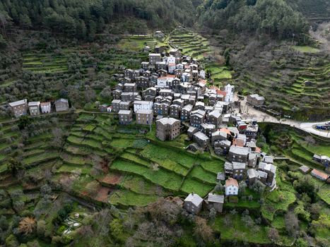Aerial view of Piódão s schist houses nestled on terraced slopes a rustic tapestry woven into the rugged landscape Piódão Arganil Portugal. Aerial view of Piódão s schist houses nestled on terraced slopes a rustic tapestry woven into the rugged landscape Piódão Arganil Portugal.