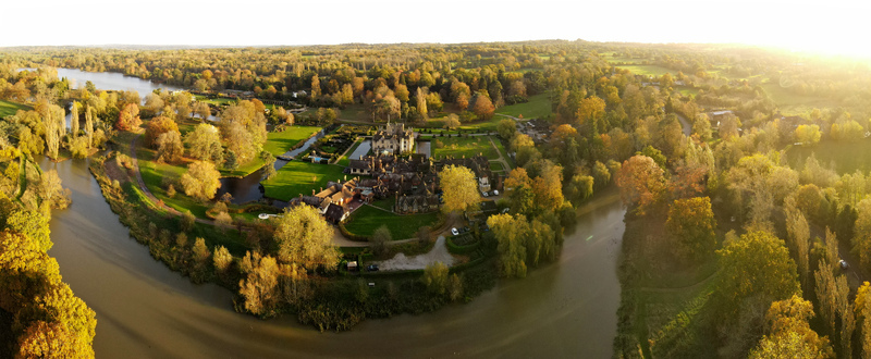 Aerial view of Hever Castle and Gardens surrounded by a moat and lush green lawns with a winding river in Hever England United Kingdom.