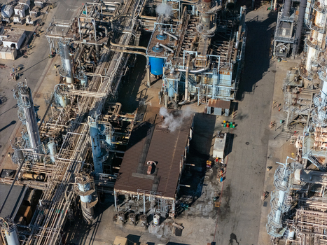 Aerial view of an industrial oil refinery complex featuring complex piping systems storage tanks and processing units in Carson California United States.