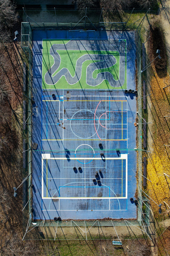 Aerial view of a multi purpose sports court with a blue surface and a small green circuit track surrounded by trees in Turin Piedmont Italy. Aerial view of a multi purpose sports court with a blue surface and a small green circuit track surrounded by trees in Turin Piedmont Italy.