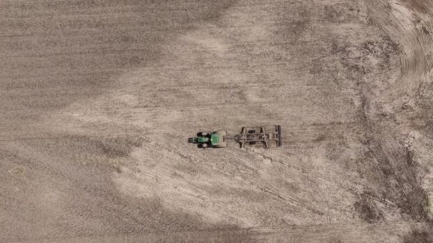 Aerial view of a green tractor working on a dry farm field Portugal. Aerial view of a green tractor working on a dry farm field Portugal.