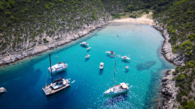 Aerial view of Smokova beach with boats anchored in turquoise waters surrounded by green hills in Vis Splitsko dalmatinska Croatia.